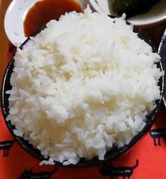 A bowl of Japanese steamed white rice (gohan) on a table served as part of a meal.
